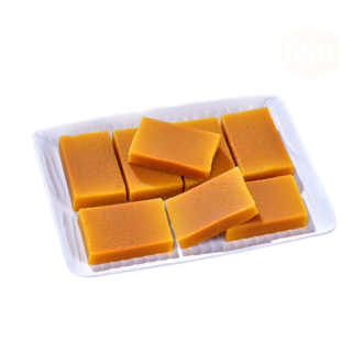 A white tray filled with golden-brown pieces of Ghee Mysore Pak, showcasing their rich texture and inviting appearance
