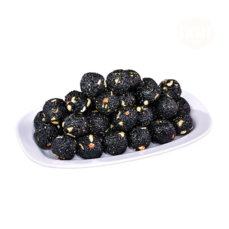 A white oval plate filled with black sesame and nut ladoos, showcasing their dark texture and nutty appearance