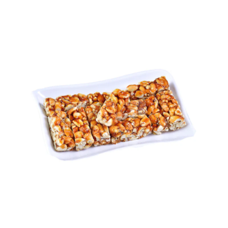 A white rectangular plate filled with crunchy peanut and caramel bars, showcasing their golden-brown color and nutty texture