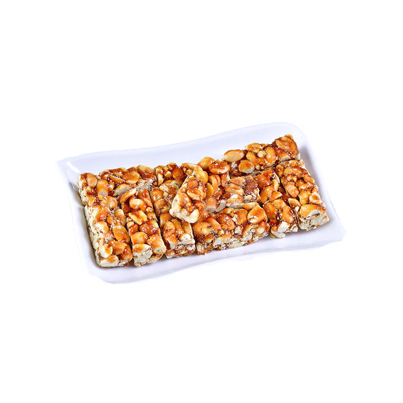 A white rectangular plate filled with crunchy peanut and caramel bars, showcasing their golden-brown color and nutty texture