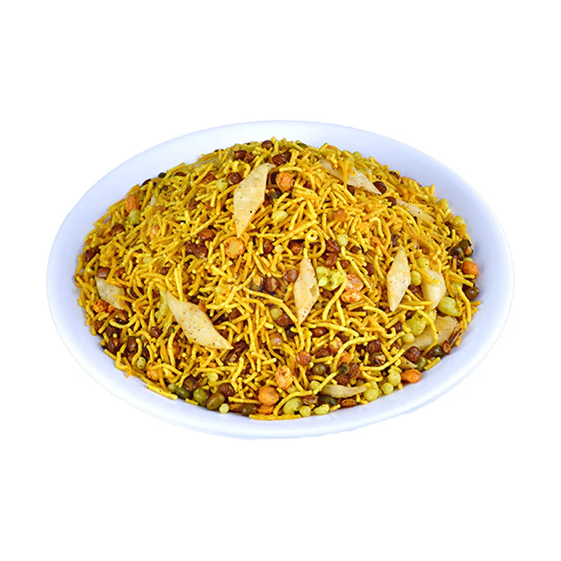 A white bowl filled with Bombay Mixture, showcasing a colorful mix of thin fried noodles, peanuts, lentils, flaked rice, and spices, garnished with fried cashew pieces.