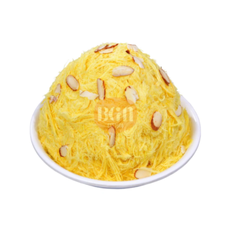 A white bowl filled with a golden-yellow Mango Soan Cake, topped with sliced almonds, showcasing its fluffy, shredded texture and appetizing appearance