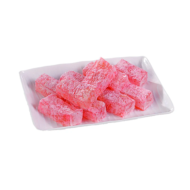 A white plate filled with vibrant pink cubes of Paneer Halwa, dusted with sugar crystals, showcasing their soft texture and inviting appearance